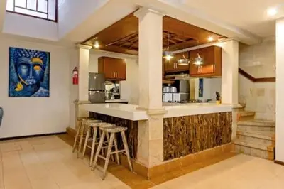 a kitchen with a counter and stools in a room at Villa Tiah in Kuta