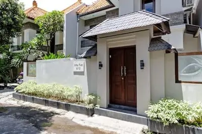a small house with a brown door in a street at Villa Tiah in Kuta
