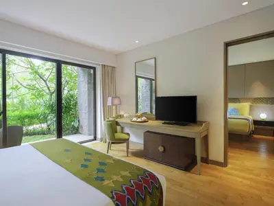 a hotel room with a bed and a desk with a television at Mövenpick Resort & Spa Jimbaran Bali in Jimbaran