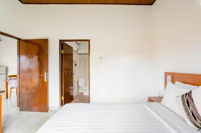 a bedroom with a white bed and a bathroom at Rumah Akira Seminyak in Seminyak