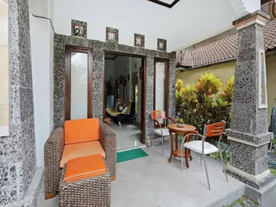 a patio with orange chairs and a table on a house at Rumah Akira Seminyak in Seminyak