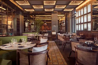 a restaurant with tables and chairs and windows at Jambuluwuk Oceano Seminyak Hotel in Seminyak