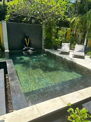 a pool in a backyard with a person sitting in the water at Amanputri Villa in Seminyak