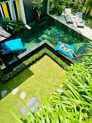 a swimming pool with two lounge chairs in a backyard at Amanputri Villa in Seminyak