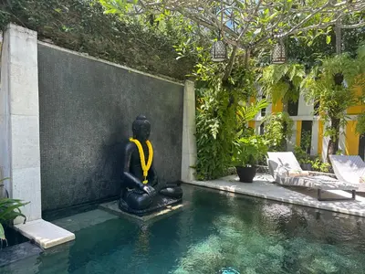 a statue sitting in the water next to a swimming pool at Amanputri Villa in Seminyak