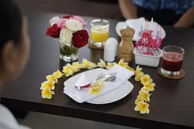 a table with a plate of food and flowers on it at The Sintesa Residence Jimbaran in Jimbaran