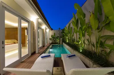 a swimming pool in the middle of a balcony with white chairs at Sithala Villa Seminyak in Seminyak