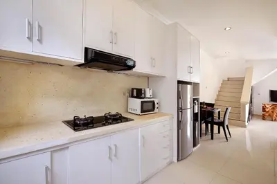 a kitchen with white cabinets and a stove top oven at Villa Lamac in Legian