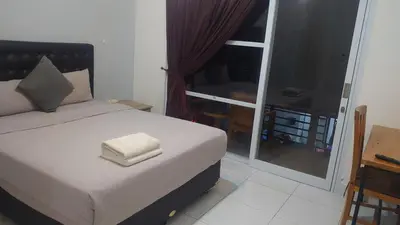 a bedroom with a bed and a balcony with a desk at Nuka Beach Inn in Kuta