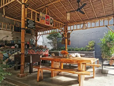 a restaurant with a wooden table in a room at Nuka Beach Inn in Kuta