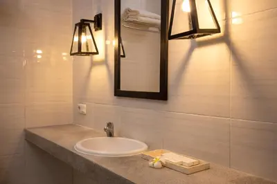 a bathroom with a sink and a mirror and lights at The Aswana Seminyak in Seminyak
