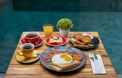 a wooden table with breakfast foods and cups of coffee at The Aswana Seminyak in Seminyak