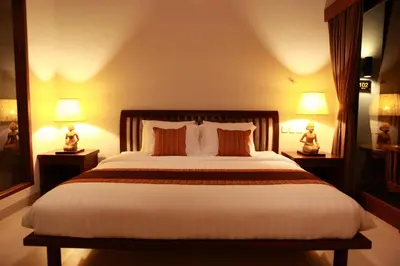 a bedroom with a large bed with two lamps at Adys Inn in Legian