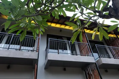 two balconies of a building with trees in the foreground at Adys Inn in Legian