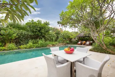 a table and chairs next to a swimming pool at Villa Roku by Nagisa Bali in Seminyak