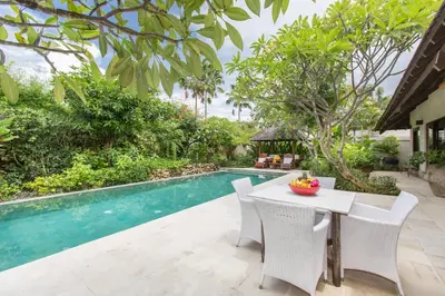 a dining area with a table and chairs next to a pool at Villa Roku by Nagisa Bali in Seminyak