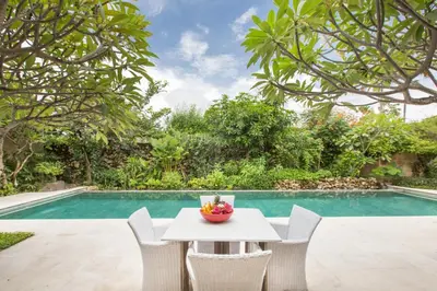 a table and chairs next to a swimming pool at Villa Roku by Nagisa Bali in Seminyak