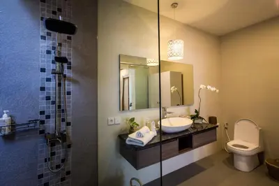 a bathroom with a sink and a toilet and a mirror at Villa Kamboja Deluxe in Seminyak