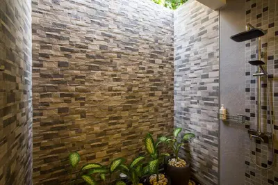 a bathroom with a brick wall with plants in it at Villa Kamboja Deluxe in Seminyak