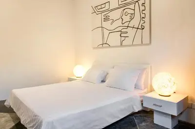 a bedroom with a white bed and a painting on the wall at Villa EMMA | heart of Seminyak | 350m Beach in Seminyak