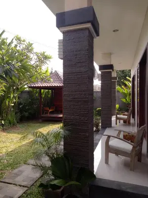 a patio of a house with a bench and a yard at Guest House Reisya in Nusa Dua