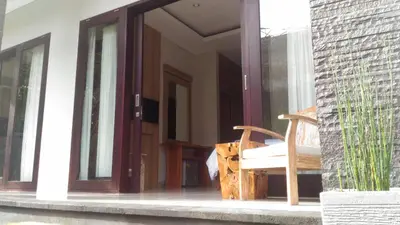 an open glass door with a chair on a porch at Guest House Reisya in Nusa Dua
