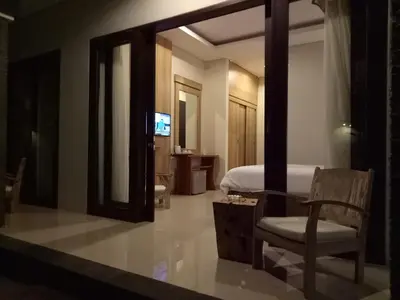 a bedroom with a bed and a mirror and a chair at Guest House Reisya in Nusa Dua