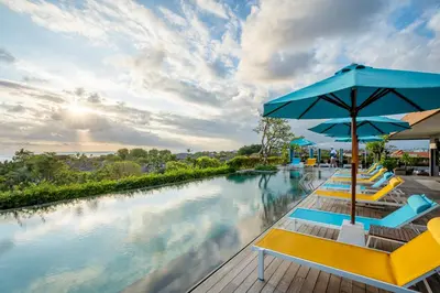 a pool at a resort with chairs and an umbrella at Rama Residence Padma in Legian