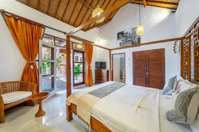 a bedroom with a bed and a chair in a room at Villa Mangga 3 chambres seminiak in Seminyak
