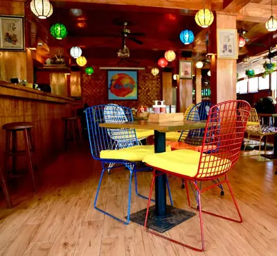 a table and chairs in a restaurant with lights at Seahouse Bali Indah Beach Inn in Kuta