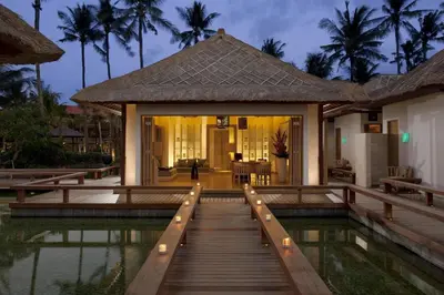 a villa with a bridge over a pool at night at Holiday Inn Express Baruna by IHG in Kuta