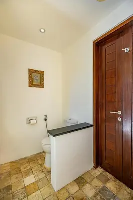 a bathroom with a toilet and a wooden door at Bali Villa Lotus in Seminyak