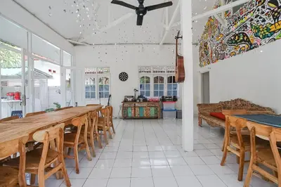 a dining room with a long table and chairs at Indopurejoy House - Komala Indah Cottages in Kuta