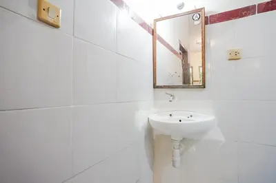 a white bathroom with a sink and a mirror at Indopurejoy House - Komala Indah Cottages in Kuta
