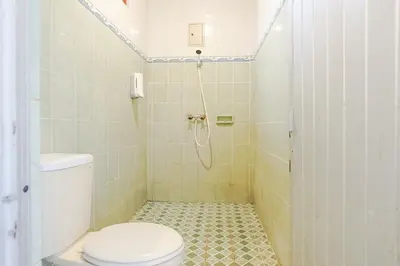 a bathroom with a toilet and a shower at Indopurejoy House - Komala Indah Cottages in Kuta