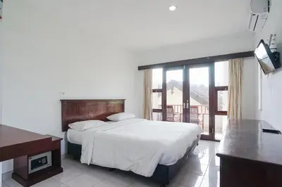 a bedroom with a large bed and a balcony at Indopurejoy House - Komala Indah Cottages in Kuta