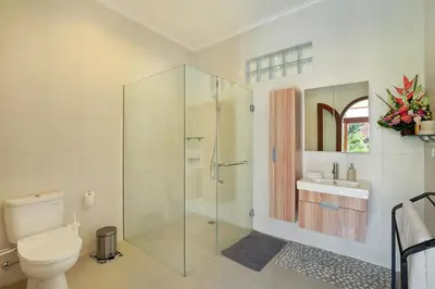 a bathroom with a glass shower and a toilet at Villa Nova in Legian