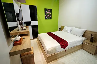 a bedroom with a bed and a green wall at D'Pande Kuta in Kuta
