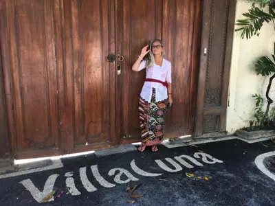 a woman standing in front of a wooden door at Villa Una in Seminyak