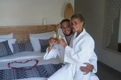 a man and woman sitting on a bed holding a wine glass at Ambermoon Villas in Seminyak