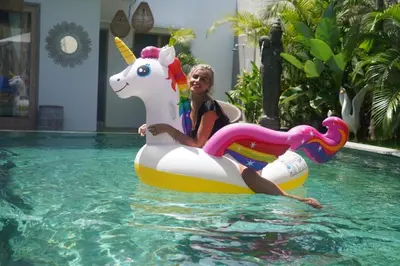 a woman riding on a unicorn ride in a swimming pool at Ambermoon Villas in Seminyak