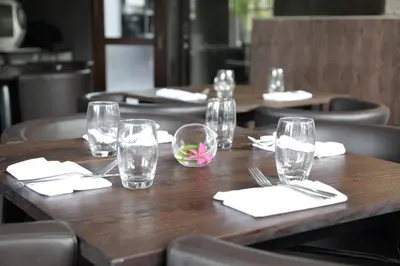 a wooden table in a restaurant with empty glasses on it at Anshel Hotel Seminyak in Seminyak