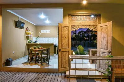 a dining room and kitchen with a table and a door at The Rani Garden Bed & Breakfast in Denpasar