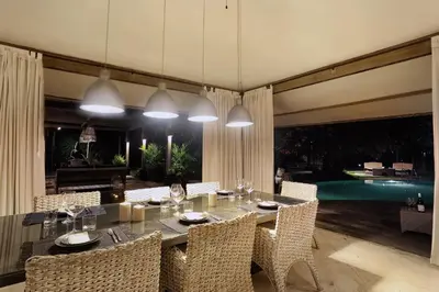 a dining room with a table and chairs and a pool at Maya Villa - Seminyak in Seminyak