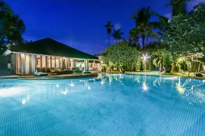 a swimming pool in front of a house at night at Maya Villa - Seminyak in Seminyak