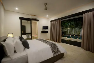 a bedroom with a large bed and a large window at Villa Maharani in Seminyak