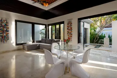 a living room with a glass table and white chairs at Villa Maharani in Seminyak