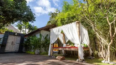 a wooden deck with a table with white curtains at Luxury Villa Kudeta 300m BEACH and heart of Seminyak in Seminyak
