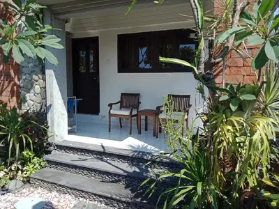 a front porch of a house with two chairs and a table at D'puja Home Stay and Spa in Nusa Dua