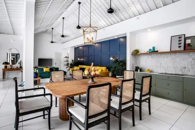 a dining room and kitchen with a wooden table and chairs at The Beach House in Canggu